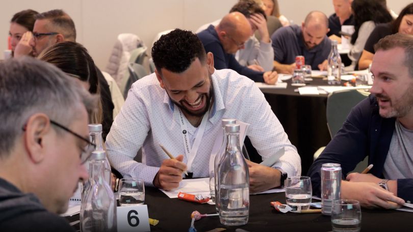 A candid photo of a Pluralsight employee at a table for an event. 